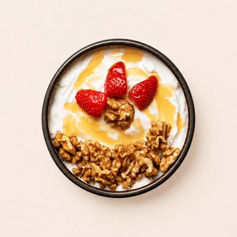 Greek yogurt bowl topped with strawberries, walnuts and honey.